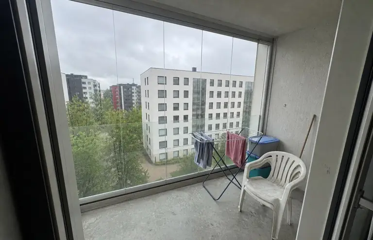 Glazed apartment balcony before: bare concrete floor, drying rack, plastic storage boxes and a single plastic chair